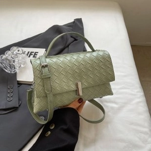 Detail of light green woven crossbody bag with silver buckle and braided texture