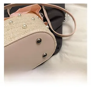 Détail du sac en paille avec base en cuir rose et pieds de protection en métal argenté