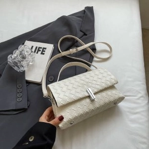 Detail view of cream woven crossbody bag with silver twist lock and leather texture