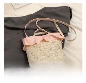 Détail du sac seau en paille avec volants roses, perles fantaisie et bandoulière