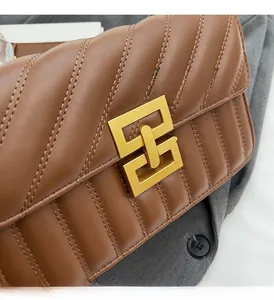 Close-up of caramel quilted leather flap bag with elegant gold geometric interlocking buckle