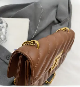 Detail of quilted brown leather bag with golden chain and metallic buckle closure