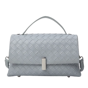 Detail of grey-blue woven leather crossbody bag with rectangle silver metal lock
