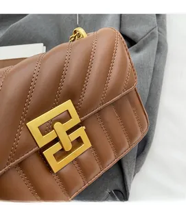Detail of brown quilted leather bag featuring a gold interlaced buckle and metal chain