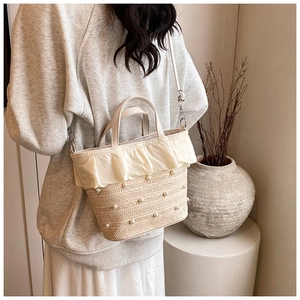 Détail d'un sac bandoulière en paille tressée avec volants crème et perles incrustées