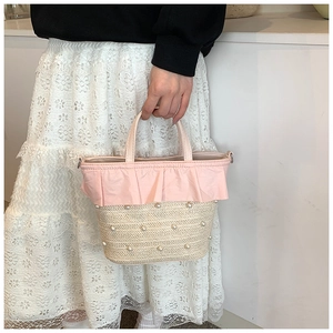 Détail du sac seau en paille tressée avec perles blanches et bordure à volants roses