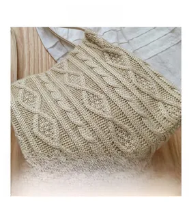 Macro detail of creamy white cable knit texture on a stylish handmade crossbody bag