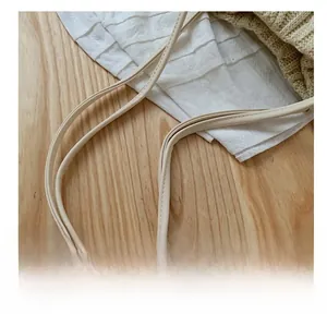 Detailed close-up of the cream leather shoulder strap with fine stitching on a wood surface