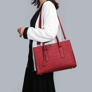 Detail of dark red tote bag featuring crocodile texture and metallic decorative buckle