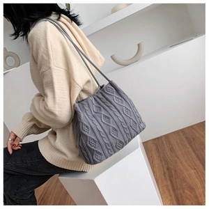 Detailed view of the gray knit shoulder bag featuring cable-stitch and diamond patterns