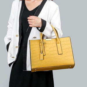 Close-up of bright yellow tote bag with crocodile texture and gold hardware details
