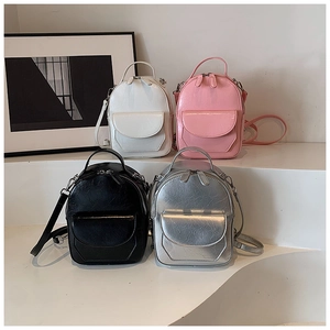 Mini zaini chic in bianco, rosa, nero e argento su un espositore minimalista