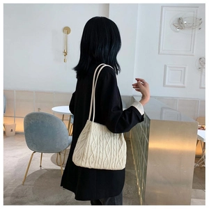 Detailed macro view of cream knitted crossbody bag with thick cable stitch texture