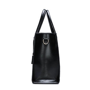 Side view of black glossy leather tote bag featuring gold-tone D-ring metal hardware