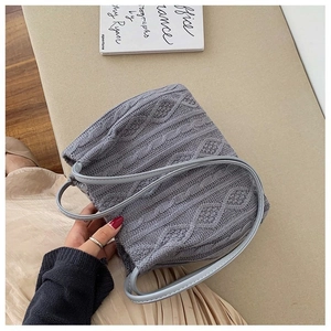 Detail of grey cable-knit handbag texture with slim leather-style handles and soft knit fabric