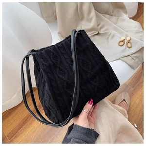 Detail of black knit shoulder bag featuring classic cable stitch and leather straps