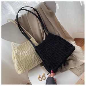 Detailed view of knitted tote bags with cable pattern and slim leather straps