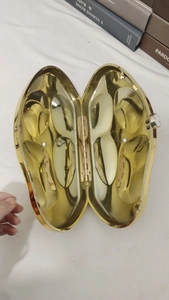 Detail view of the polished golden oval evening bag with open interior and metal hinge
