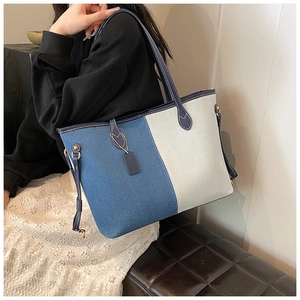 Modern denim and canvas tote bag featuring vertical patchwork and adjustable leather strap