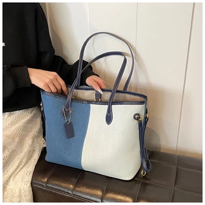 Close-up of the two-tone denim tote bag with leather straps and gold metal buckles