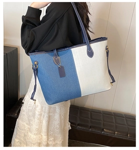 Detail of blue and white patchwork denim tote bag with leather handles shown on model