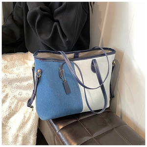 Detail shot of the two-tone blue denim tote bag featuring premium leather trim and handles