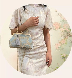 Close-up of vintage floral embroidery on satin evening bag with metal frame and silk tassel