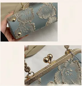 Detail of floral embroidery on blue satin bag with golden metal clasp and base studs
