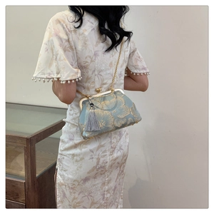 Detailed view of blue floral embroidery evening bag with gold clasp and grey silk tassel