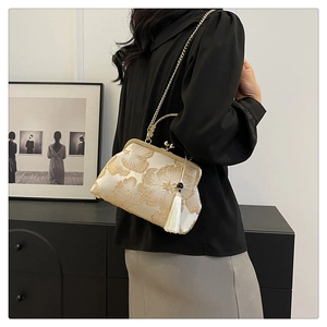 Detail of cream evening bag with gold floral embroidery, metal handle, and silk tassels