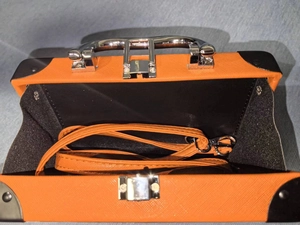 Detail view of orange Saffiano texture crossbody bag with silver hardware and interior strap