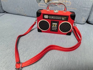 Detailed close-up of a vintage radio-shaped red handbag on a blue fabric background
