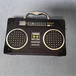 Detail of creative vintage radio shaped handbag with metallic handle and printed graphics