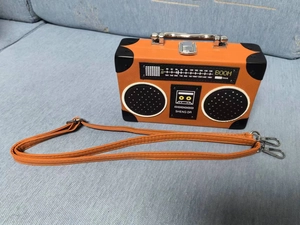Top-down view of orange vintage radio style bag with speaker detail and metal handle