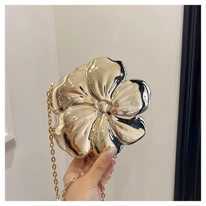 Macro detail of 3D gold flower evening clutch bag with high-polish metallic surface and chain