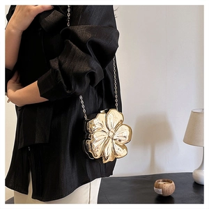 Close-up of golden flower-shaped metal evening clutch bag with refined chain strap
