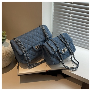 Close-up of denim quilted flap bag with silver twist lock and classic metal chain strap