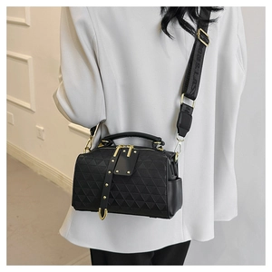 Detail of black quilted crossbody bag featuring 3D triangle texture and gold hardware