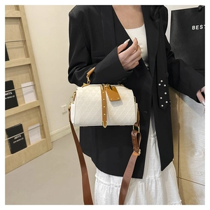 Close-up of quilted crossbody handbag with leather handle and patterned shoulder strap