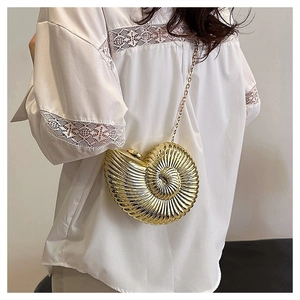 Detailed shot of golden conch-shaped evening bag with metallic spiral texture and chain
