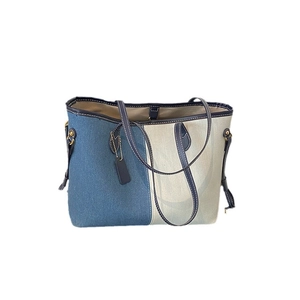 Blue denim and beige canvas patchwork tote bag with dark blue leather handles