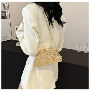 Detail of gold crescent chain bag with hammered texture on white blazer suit