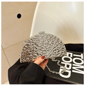 Close-up of a silver semi-circle clutch bag with hammered metal texture and chain strap
