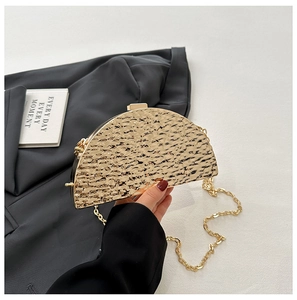 Detailed view of semi-circular gold evening bag with metallic hammered texture and chain
