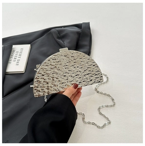 Close-up of a silver semi-circular evening clutch bag with hammered metal texture and chain