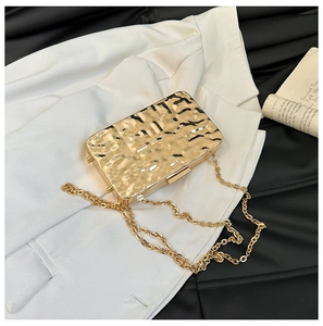 Detail der goldenen Metall-Clutch mit Wasserwellen-Textur und feiner Kette