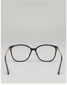 Detail view of black polygon frame glasses with slim gold metal temples on a grey background