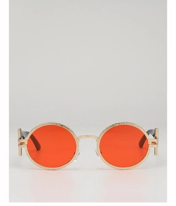 Close-up of retro round orange lenses with hammered gold metal frames and premium texture