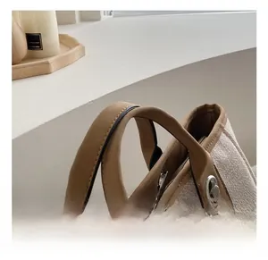 Detail view of cream canvas tote bag with brown leather handles and chain accent