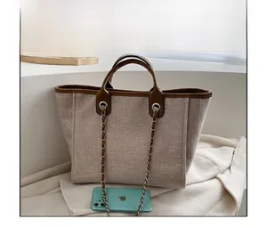 Detailed comparison of beige canvas tote bag with brown leather trim and a smartphone